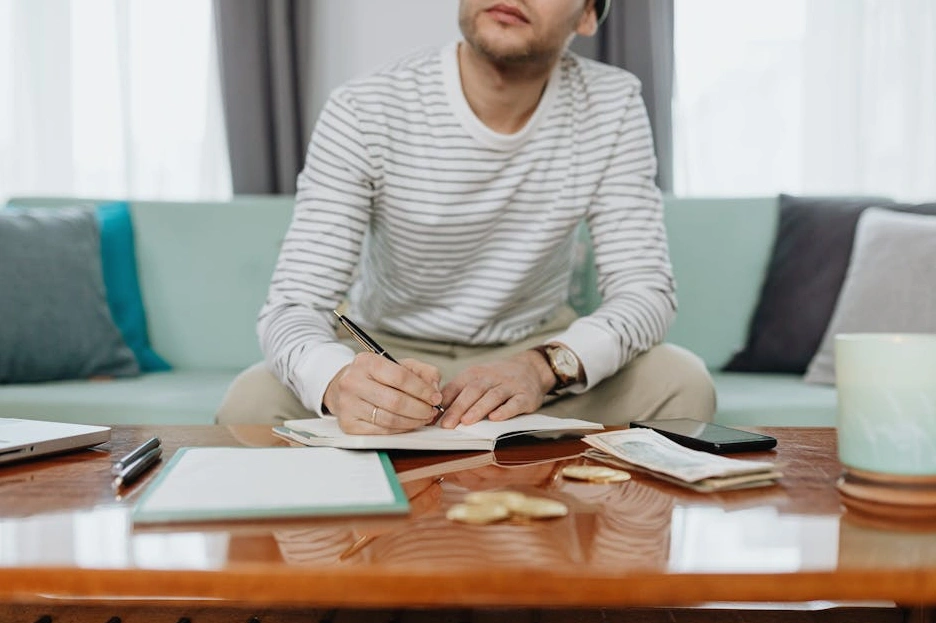 A person carefully reviewing their budget on a laptop with receipts and a calculator nearby.